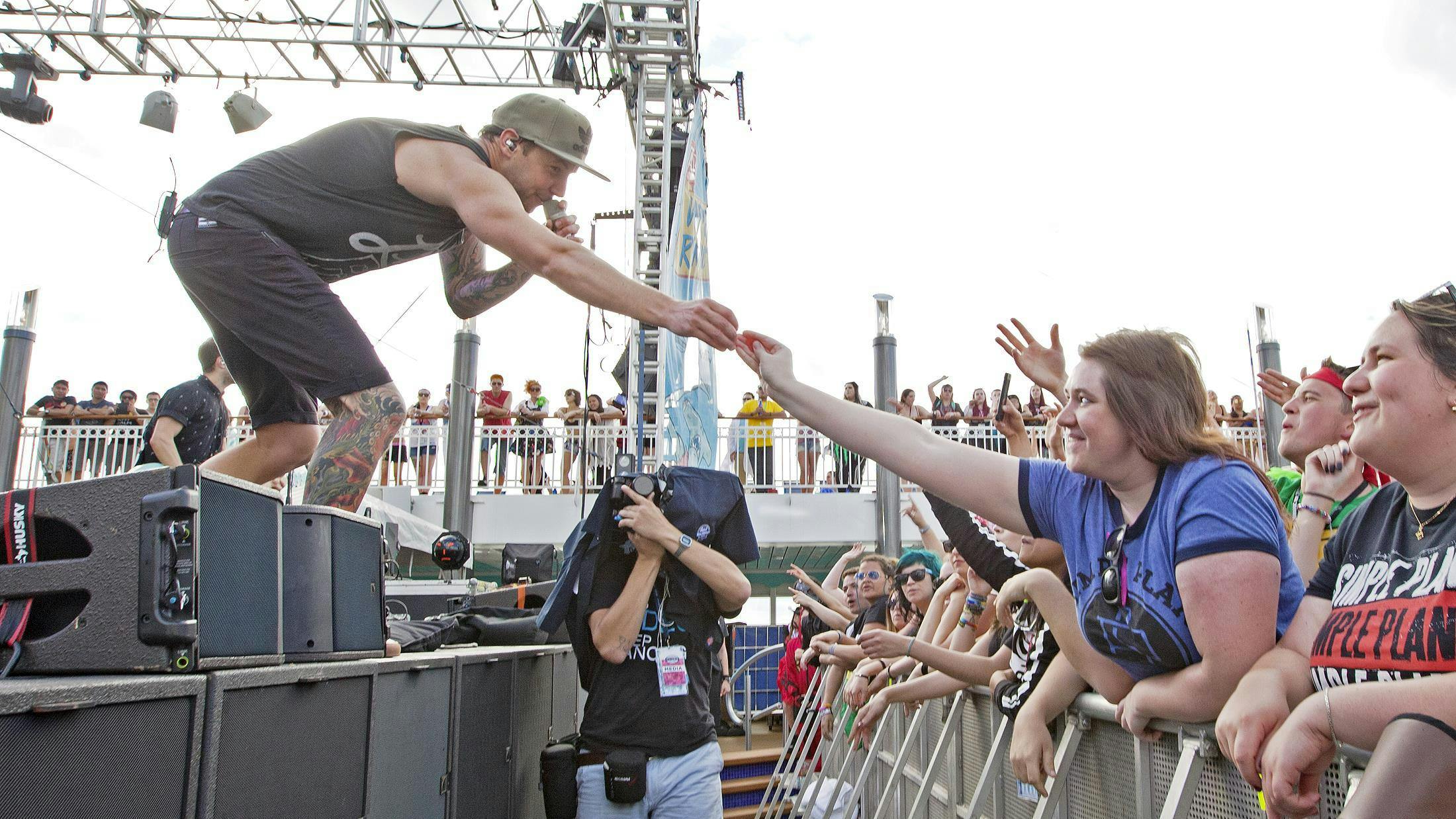 Simple Plan singer Pierre Bouvier hands a guitar pick to a fan in the front row.