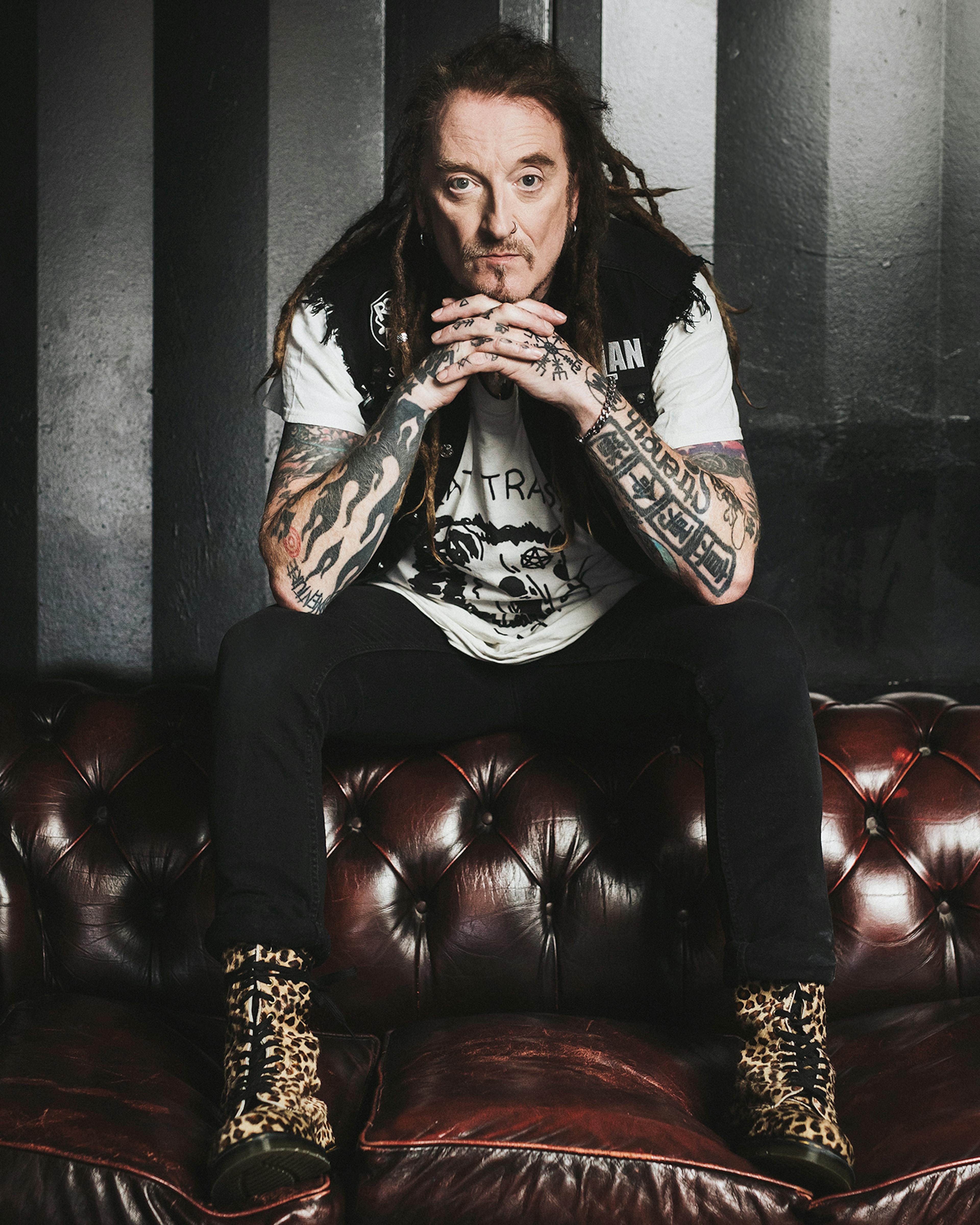 A photo of Wildhearts frotman Ginger sat on a leather settee in leopard-print boots